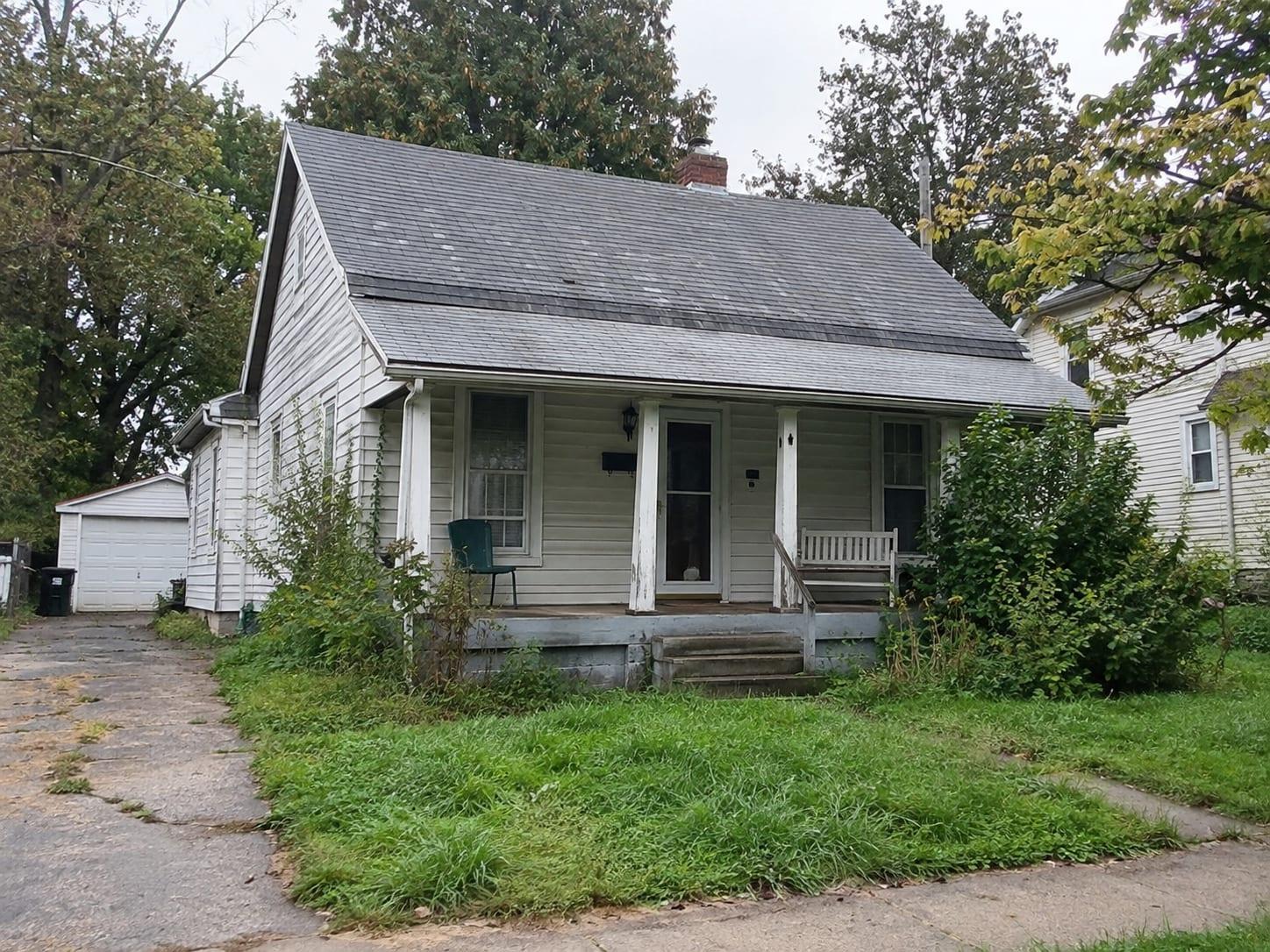 Weathered single-family home with peeling paint, an aging roof, and an overgrown front yard — the kind of as-is property PalmSide buys.